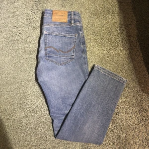 Ljusblå jeans från Jack and Jones  - Säljer ett par klassiska ljusblå jeans från Jack and Jones med raka ben och normal passform. Jeansen har fem fickor, snygga kontrastsömmar. Perfekta till vardags för en avslappnad stil.