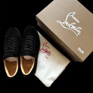 Svarta sneakers med nitar från Christian Louboutin - Säljer ett par svarta sneakers från Christian Louboutin med ikoniska röda sulor och svarta nitar på tån.helt ny oanvända.tillkommer box dustbag extra nitar och kvitto.pris kan diskuteras 