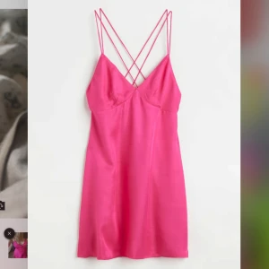 Rosa satin klänning med smala axelband - Säljer en snygg rosa kortklänning i satin med tunna dubbla axelband som korsas i ryggen. Klänningen har en figurnära passform och är perfekt för sommarens alla tillfällen. Aldrig använd💕