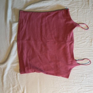 Rosa ribbad linnetopp från SHEIN - Säljer en rosa ribbad linnetopp från SHEIN med smala axelband. Toppen har en enkel och stilren design, perfekt att matcha med jeans eller kjol. Mjuk och stretchig i materialet för en bekväm passform. Dubbelsidigt material över bysten