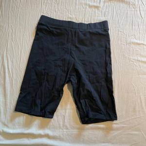 Svarta cykelshorts från H&M - Svarta cykelshorts från H&M med elastisk midja. Perfekta för träning eller som ett bekvämt basplagg. Mjukt och stretchigt material som sitter tight mot kroppen.
