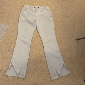 Vita bootcut-byxor från BikBok - Snygga vita bootcut-byxor från BikBok med klassisk passform och låg midja. Byxorna har fickor fram, bälteshällor och stängs med dragkedja och knapp. Perfekta för en stilren look. OPS. De finns några defekter på byxorna men inget som jag skulle säga syns om man inte kollar på nära håll då förstås,(smutsfläckar). :)