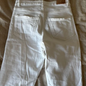 Vita bootcut jeans med slits - Vita jeans från Gina tricot i nytt skick. Jeansen är lite tjockare i materialet och har både utsvängda ben och en slits i slutet. Modellen är midwaist.