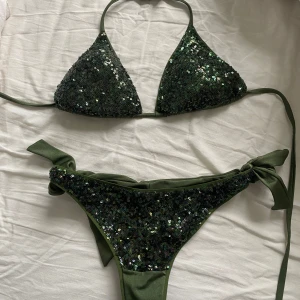 Mörkgrön bikini med paljetter calzedonia  - Säljer en snygg mörkgrön bikini med paljetter på överdelen och knyt i sidorna på underdelen. Bikinin har trekantsmodell storlek s från calzedonia 
