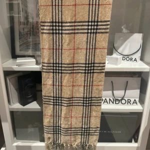 Burberry halsduk, rutig halsduk med fransar - Snygg beige halsduk med klassiskt rutigt mönster i svart, vitt och rött. Halsduken har fransar i ändarna och känns både stilren och tidlös. Perfekt accessoar för att lyfta din outfit. Kom med prisförslag!