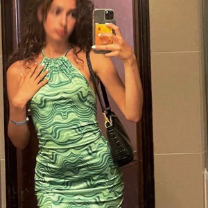 Grön mönstrad halterneckklänning - Säljer en snygg grön halterneckklänning med vågigt mönster i olika gröna nyanser. Klänningen är tight och kort. 