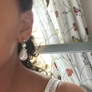 Silverfärgade örhängen med pärldetaljer - Snygga örhängen i silverfärg med två pärlor, en mindre och en större droppformad. Örhängena har en elegant design med en liten glittrig detalj upptill. Gjort själv med användning av andra smycken. Perfekta för att lyfta din look! 