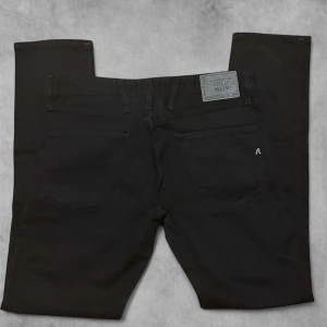 Svarta Replay Anbass jeans - Säljer ett par svarta Replay Anbass jeans med klassisk femficksdesign. Perfekta för dig som gillar stilrena och tidlösa jeans. Pris kan diskutera
