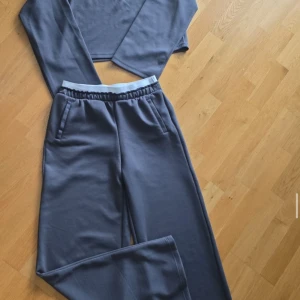 Mörkgrå mjukis tröja från Amisu - Igen sett!!! Mörkgrå mjukis tröja från Amisu med elastisk midja och sidofickor. Byxorna har en avslappnad passform och är perfekta för en chill stil. Materialet är mjukt och bekvämt, perfekt för vardagsbruk.