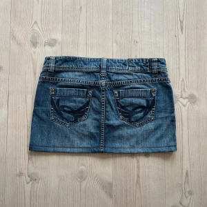 Blå lågmidjad jeanskjol  - Blå lågmidjad jeanskjol från Esprit i fint skick. Kan inte hitta storlek men skulle säga S/M. Tvärs över midjan är det 42 cm och den är 31 cm lång (längs med sidan) Använd gärna köp nu!
