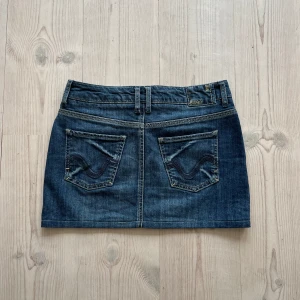 Mörkblå lågmidjad jeanskjol  - Blå lågmidjad jeanskjol från Esprit i fint skick. Kan inte hitta storlek men skulle säga S, kanske passar M också. Tvärs över midjan är det 38 cm och den är ca 33 cm lång (längs med sidan). Använd gärna köp nu!