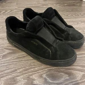 Axel arigato 360 laceless - Stilrena svarta sneakers från Axel Arigato i mocka med diskret logga i guld på sidan. Köpta för 2500 på deras hemsida. box och allt det originala medföljer. pris kan diskuteras vid snabbaffär