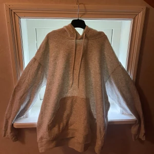 Ljusgrå hoodie från H&M i storlek M - En  ljusgrå hoodie från H&M med stor känguruficka och huva med snörning. Tröjan är varsamt använd och vill sälja för att jag köpte en ny hoodie så jag behöver inte denna längre
