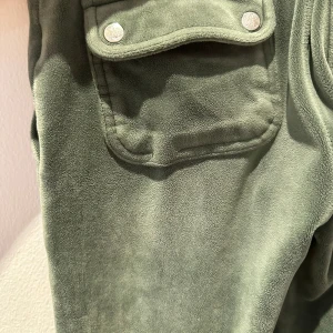 Gröna mjukisbyxor Juicy Couture XXS - Mörkgröna mjukisbyxor från Juicy Couture i supermjuk fleece. Byxorna har stora fickor med lock och silverfärgade knappar, samt broderad JC-logga på ena fickan. Perfekta för en chill och avslappnad look.