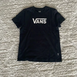 Svart Vans t-shirt med logga - Svart t-shirt från Vans i storlek XS med klassisk vit Vans-logga på bröstet. T-shirten har rund halsringning och korta ärmar. Perfekt för dig som gillar streetwear och enkel stil.