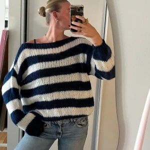 Randig stickad oversized tröja - Säljer en chunky stickad tröja med breda marinblå och vita ränder. Tröjan har en oversized passform, lång ärm och bred halsringning som ger en avslappnad vibe. Perfekt att slänga på sig över jeans för en cool och mysig look.