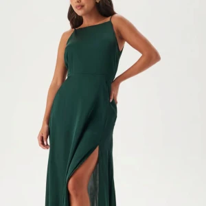 Mörkgrön långklänning med slits - Elegant mörkgrön långklänning i satin, hög slits framtill och snygg draperad öppen rygg. Perfekt för dig som vill sticka ut med stilren look. Klänning är endast använd en gång men ser ut som ny💕