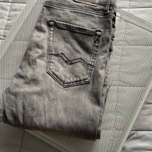 Grå Replay jeans straight fit - Snygga grå jeans från Replay med klassisk femficksdesign och raka ben/straight leg. Jeansen har svarta detaljer, diskret Replay-logga på fickan och är tillverkade i mjuk bomullsdenim. Det ända lilla felet är en liten blå fläck på framsida lår, som jag dock tror att går bort i hårdtvätt, vanish. Jeansen kostade från början 800kr, köpta från KIDSBRANDSTORE.