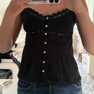 Svart spetslinnetopp med knappar - Supersöt svart topp ifrån zara som knappt är använd, max 3 gånger så helt i nyskick