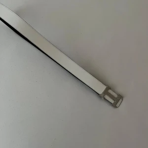 Vitt skärp med silverfärgat H-spänne - Snyggt vitt bälte med ett stilrent H-format spänne i silverfärg. Bältet har en slät yta och är gjort i skinn. Perfekt accessoar för att lyfta din outfit med en modern touch.