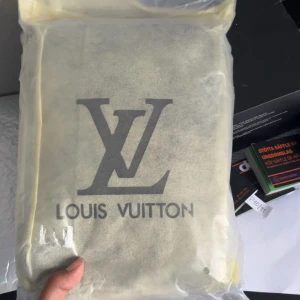 Svart axelväska från Louis Vuitton - Säljer en svart axelväska från Louis Vuitton med klassiskt monogrammönster i präglat skinn. Väskan har en justerbar axelrem med logga och ett mindre fack som kan fästas på remmen. Perfekt för dig som vill ha en stilren och lyxig accessoar.