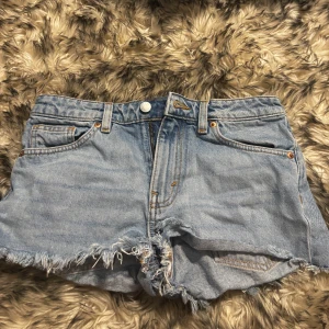 Ljusblå jeansshorts från Monki - Snygga ljusblå, lågmidjade jeansshorts från Monki med fransig, rå kant och klassisk femficksmodell. Har haft på mig dessa 2 gånger förut. Nästan helt nya!