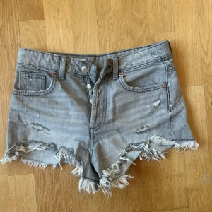 Grå slitna jeansshorts med fransar - Snygga grå jeansshorts med låg midja och slitna detaljer. Shortsen har fransig kant nertill och flera coola revor. Perfekta för sommaren!!💕💕💕 Knappt använda, nypris ca 400!!