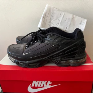 Nike Tuned Air svarta sneakers - Svarta Nike Tuned Air sneakers med cool futuristisk design och tydliga detaljer i mesh och syntet. Skorna har snörning, synlig luftdämpning i sulan och diskreta vita loggor. Perfekta för dig som gillar streetwear och vill ha en chunky, sportig look.