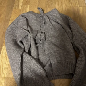 Grå stickad kofta med knytband - Mysig grå stickad kofta med breda ribbade ärmar och snygga knytband i ryggen. 