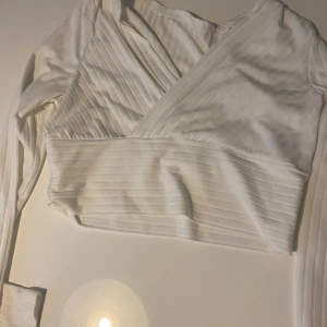 Vit omlottopp med ribbade detaljer - Snygg vit omlottopp med ribbade ränder och lång ärm.  ☺️