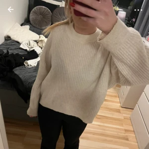 Beige ribbstickad tröja från H&M - Supermysig beige ribbstickad tröja från H&M i storlek M. Tröjan har en relaxed, lite oversized passform med rund halsringning och långa ärmar. Perfekt att slänga på sig när det är kyligt ute och funkar till både jeans och leggings.