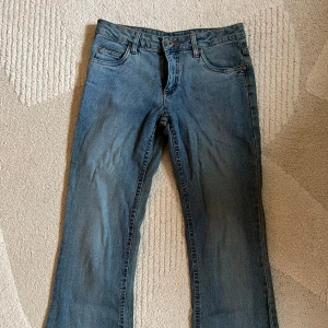 Blå lågmidjade bootcut jeans från Arizona - Snygga blå jeans från Arizona med klassisk bootcut-passform. Jeansen har fem fickor, ljus tvätt och coola sömdetaljer på bakfickorna. Perfekta för dig som gillar en avslappnad men ändå trendig look.