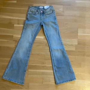 Blå bootcut jeans från ONLY - Snygga ljusblå jeans från ONLY med bootcut passform och låg midja. Jeansen har klassisk femficksdesign, dragkedja och knapp framtill samt slits nertill på benen. Säljer då de inte passade mig. De är oanvända🩵