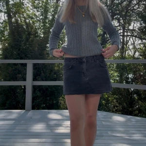 Grå kabelstickad tröja  - Snygg grå kabelstickad tröja från Lexington med diskret logga på bröstet. Tröjan har rund hals, lång ärm och ribbade muddar. 