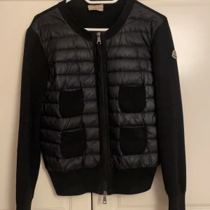  cardigan jacka från Moncler - Snygg cardigan jacka från Moncler med quiltad framsida och fyra stickade fickor. Jackan har långärmade stickade ärmar, rund halsringning och dragkedja framtill. Perfekt för dig som gillar en clean och stilren look med exklusiv känsla. Passar mig som vanligtvis har storlek S-M i jackor  hör av er vid minsta fundering 🌸