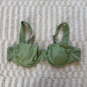 Grön bikiniöverdel  - Grön, lite lätt skimrig, bikiniöverdel från Bik Bok med breda axelband och bygel för extra stöd. Tillverkad i mjuk och stretchig polyesterblandning. 