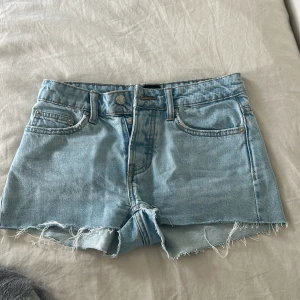 Ljusblå jeansshorts från 157 - Snygga ljusblå jeansshorts från 157 med råa, fransiga kanter och klassisk femficksdesign. Shortsen har en låg midja. Storlek XXS men passar XS.