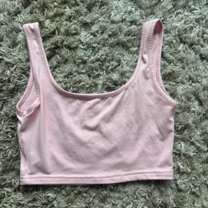 Ljusrosa croppad linnetopp - Söt ljusrosa croppad linnetopp med breda axelband och rundad urringning. Tillverkad i mjuk bomull som känns skön mot huden. Perfekt att styla med jeans eller kjol för en chill look.