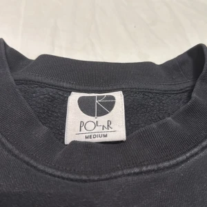 Svart sweatshirt från Polar Skate Co - Svart sweatshirt från Polar Skate Co i storlek medium. Tröjan har rund hals, broderad logga på bröstet och ribbade muddar vid ärmslut och nederkant. Tillverkad i mjuk bomull för en skön och avslappnad stil. 