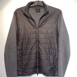 Grå quiltad cardigan jacka Massimo Dutti - Snygg grå cardigan jacka från Massimo Dutti med quiltad framsida och stickade ärmar och rygg. Jackan har dragkedja framtill, ståkrage och två fickor med dragkedja. Perfekt för lager-på-lager och stilren look.