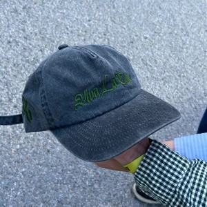 Soppirobygget keps limited edition  - Snygg svart keps i tvättad bomull med grön broderad text framtill. Klassisk böjd skärm och justerbar rem baktill för perfekt passform. Perfekt accessoar för en chill streetwear-look.