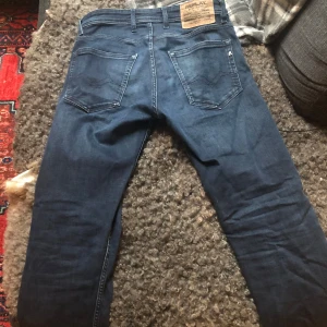 Mörkblå Replay jeans, storlek 28 - Säljer ett par mörkblå jeans från Replay i klassisk femficksmodell. Jeansen har raka ben, normal passform och snygga detaljer vid fickorna. Perfekta för dig som gillar stilrena och tidlösa jeans. Materialet är jeans med en skön känsla.