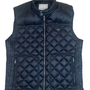 Moncler ”Rod” vest  - Moncler väst Blacklabel storlek 4 / L-Xl. Skick 8/10 finns en scratch samt mini pine hole. Pris 2390! Finns att köpa på våran hemsida, Fashionels.com