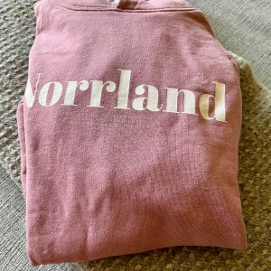 Rosa hoodie från SQRTN Company - Sparsamt använd.✌️Säljer en rosa hoodie från SQRTN Company med vit text 'Norrland' på bröstet, broderad hjortron på ärmen och vit snörning i huvan. Tröjan har magficka och ribbade muddar. Perfekt för dig som gillar norrländsk stil och vill ha något bekvämt och snyggt. Sitter som M. Nypris 900kr.