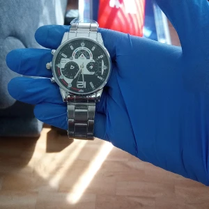 Stilren silverfärgad klocka med svart urtavla - Klocka med robust länkarmband i silverfärgad metall och svart urtavla med vita och röda detaljer. Urtavlan har flera dekorativa små ur och tydliga siffror. Perfekt accessoar för dig som gillar en sportig och modern look.