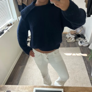 Mörkblå stickad tröja med krage - Säljer en mörkblå stickad tröja med bred krage och långärmad modell. Tröjan har en loose passform och är croppad i midjan, vilket ger en chill och trendig vibe. Perfekt att styla med höga jeans eller kjol för en snygg look.lige nopprig men inget man lägger mycket märke till.