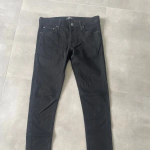 Svarta slim jeans Jack & Jones - Svarta slim fit jeans från Jack & Jones, modell Glenn. Klassisk femficksdesign med smal passform och normal midja. Snygga och stilrena jeans i bomullsmix som passar perfekt till sneakers eller boots.