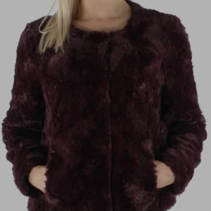 Mörk vinröd pälsjacka från veramoda - Säljer en fluffig och mjuk pälsjacka i mörk vinröd färg. Vera Moda. Jackan har rund halsringning, långa ärmar och en clean look utan synliga knappar. Perfekt för dig som vill ha en cozy och stylish vibe under kyliga dagar. Och ni vet att hösten är around the corner så den är perfect!! Så skön eftersom det är silkes innerst. aldrig använt den!! Original pris 600 kr.