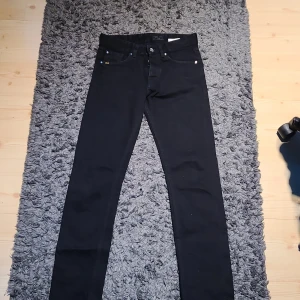 Tiger of Sweden jeans - Svarta jeans från Tiger of Sweden i modellen Alex. Snygg, smal passform med klassisk femficksdesign och diskreta detaljer. Jeansen är tillverkade i bomull med en stretchig känsla för extra komfort. Perfekta för dig som gillar stilrena och slimmade byxor. Nypris: 1600 mitt pris: 500