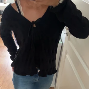 Svart stickad kofta Odd Molly med knyt - Supersöt svart stickad kofta från Odd Molly med knyt framtill och snyggt hålmönster. Koftan har lång ärm, v-ringning och volangkant nertill och längst ner på armen. Storlekn 2 motsvarar ungefär M. Har oftast xs i storlek därför lite lång i armarna och en aning stor men jag brukar vika upp de vilket funkar utmärkt😊Är i fint skick❤️Hör av dig för fler bilder eller för frågor!